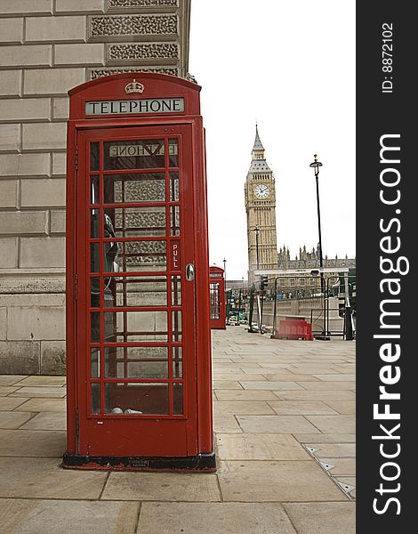 The famous Big Ben with a traditional telephone booth in front of it. The Big Ben is located in London England.