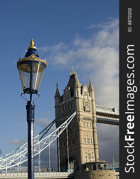 A lamppost with a part of the tower bridge in the back. This picture is taken in London England. A lamppost with a part of the tower bridge in the back. This picture is taken in London England