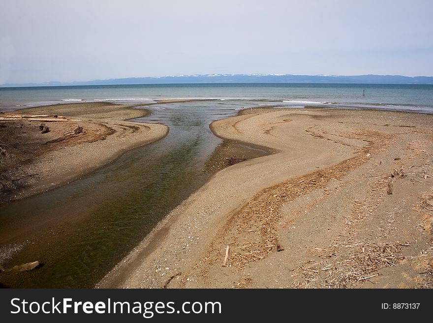 The mouth of a small river opening up into Puget Sound, Washington, with Victoria Island, Canada in the distance. The mouth of a small river opening up into Puget Sound, Washington, with Victoria Island, Canada in the distance.