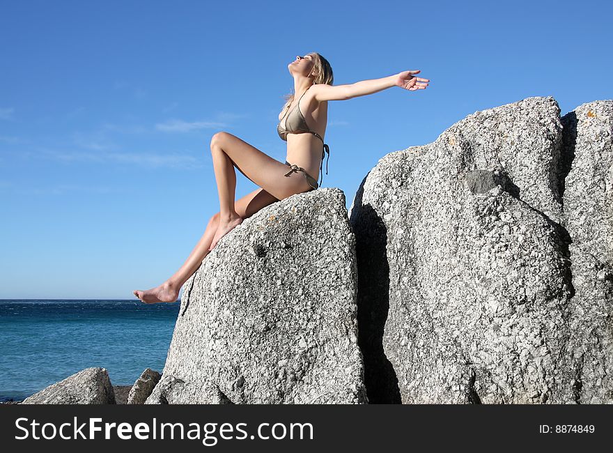 Young woman sitting on a sea rock. Young woman sitting on a sea rock