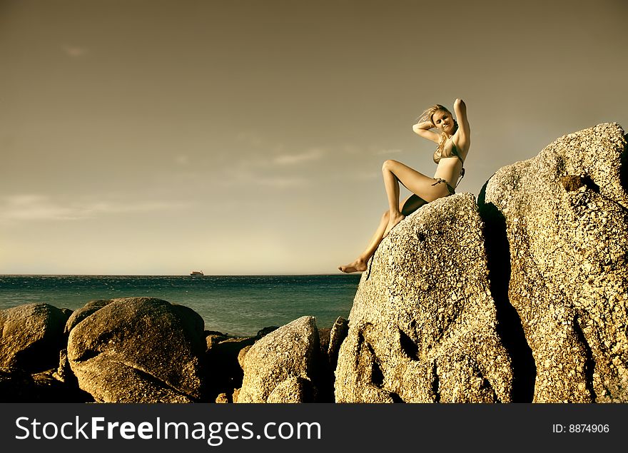 Young woman sitting on a sea rock