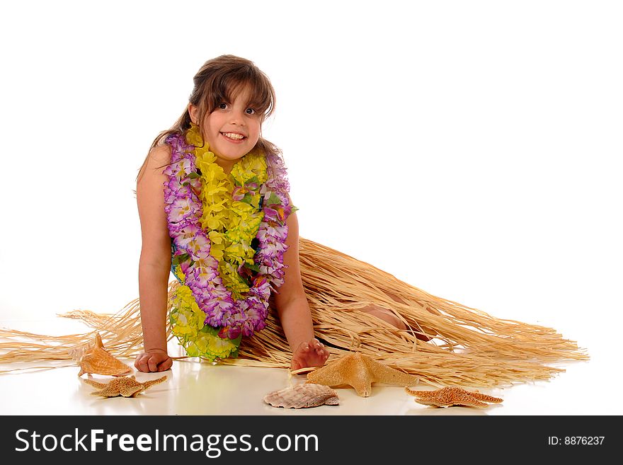 A happy elementary girl relaxing in her grass skirt and leis.  Isolated on white. A happy elementary girl relaxing in her grass skirt and leis.  Isolated on white.