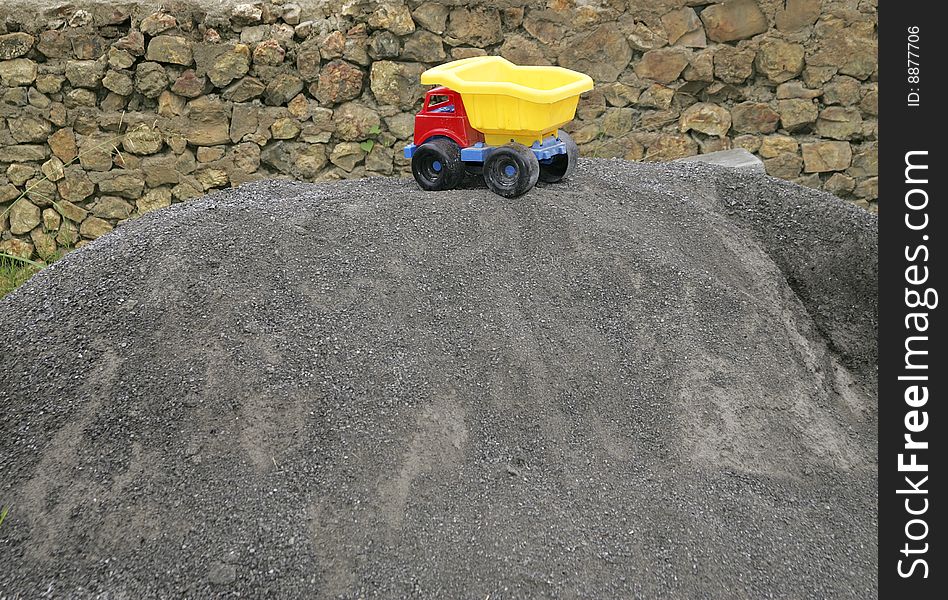 One red blue and yellow young child's toy truck on a sand pile