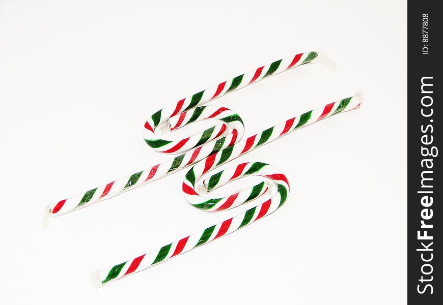 A picture of four red and green candy canes in an intertwined figuration to make an unique design.