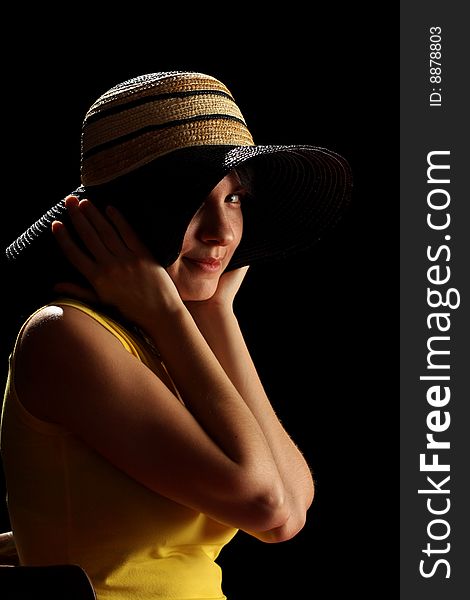 Young brunette girl and straw hat, isolated on black