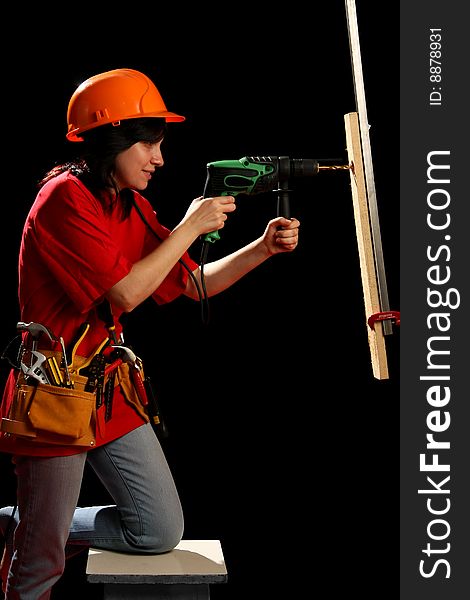 Young woman with work tools and drill, isolated on black