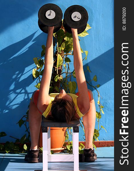 Woman doing exercises with dumbbells in the fitness center. Woman doing exercises with dumbbells in the fitness center