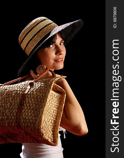 Young woman with straw hat and bag, isolated on black