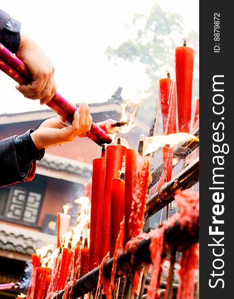 A picture of male hands hold joss sticks to burn and flames of candles. A picture of male hands hold joss sticks to burn and flames of candles