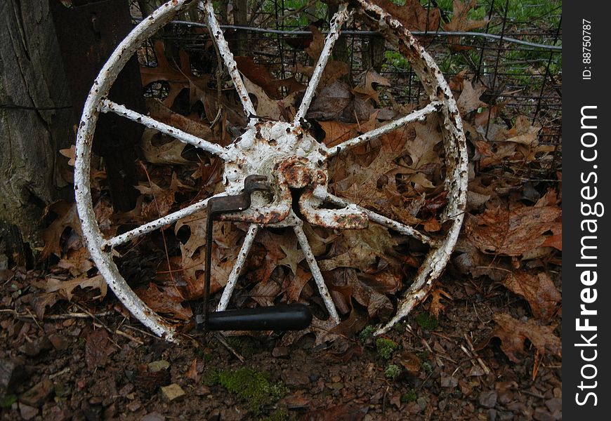 An old rusted wagon wheel against a fence. An old rusted wagon wheel against a fence
