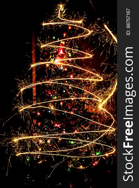 A long exposure of sparklers in front of a Christmas tree. A long exposure of sparklers in front of a Christmas tree.
