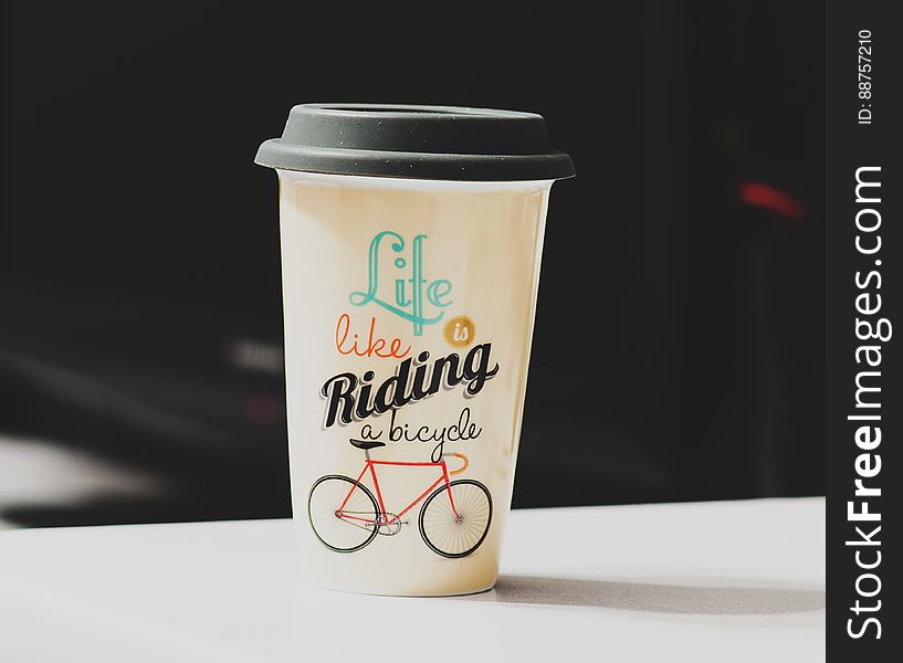 A paper coffee cup with lid and a bicycle illustration. A paper coffee cup with lid and a bicycle illustration.