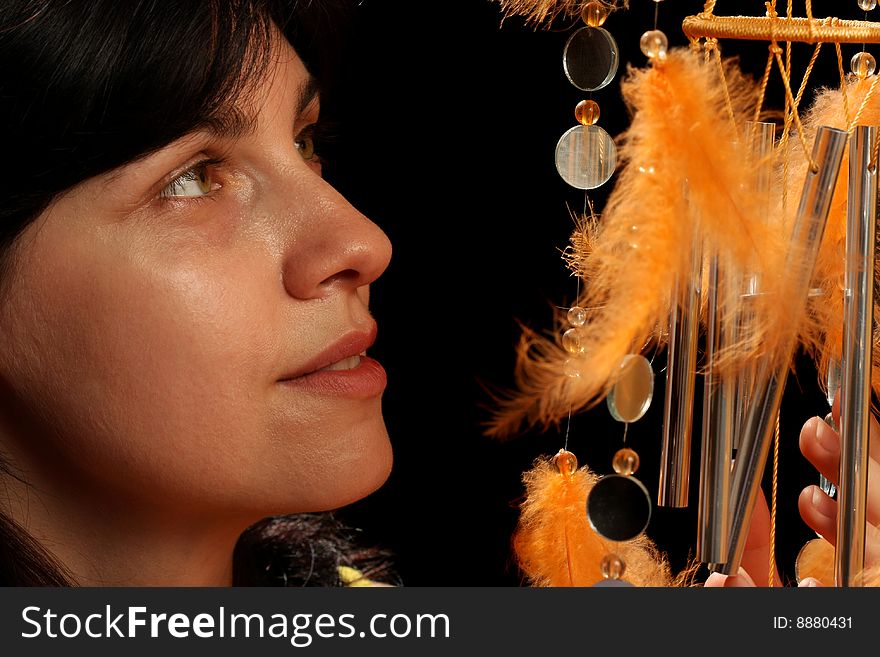 Young brunette and wind chime, on black background