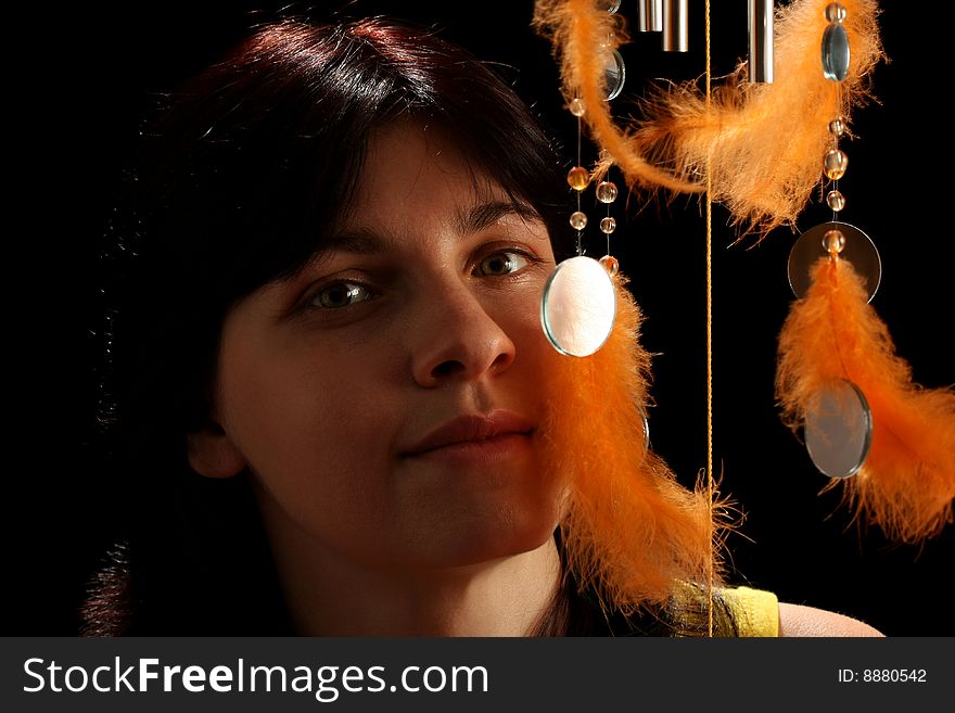 Young brunette and wind chime, on black background