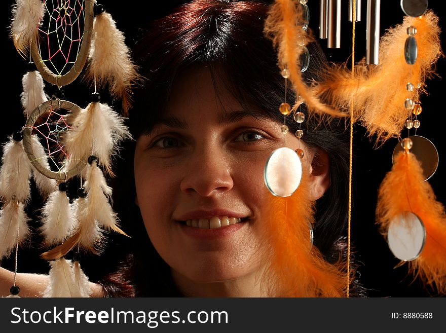 Young brunette with wind chime and dream catcher, on black background