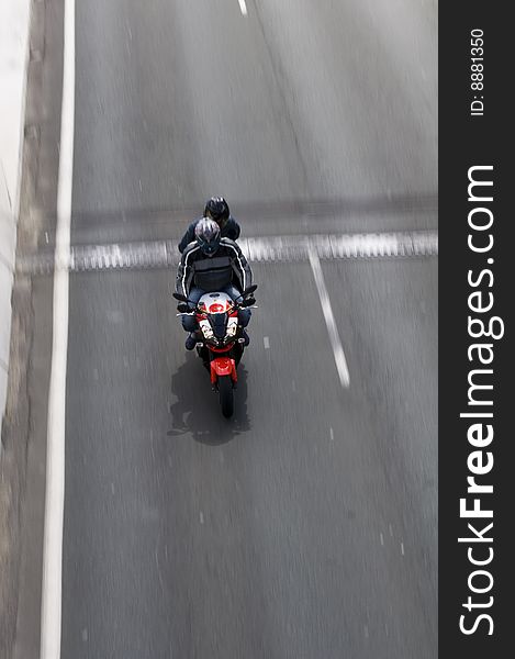 Motorcyclist speeding down road with a passenger on the back taken from above with lots of motion blur. Motorcyclist speeding down road with a passenger on the back taken from above with lots of motion blur