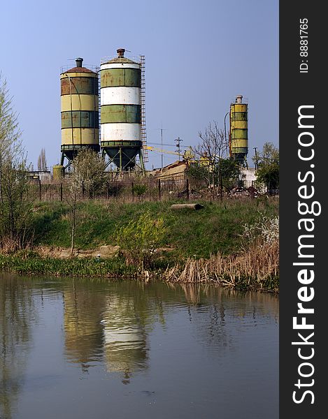 A view with an abandoned industrial facility and water reflection