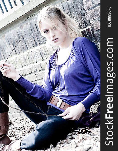 Young blond girl outside on a street posing against the wall. Young blond girl outside on a street posing against the wall