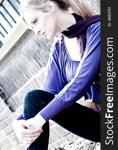 Young blond girl outside on a street posing against the wall. Young blond girl outside on a street posing against the wall