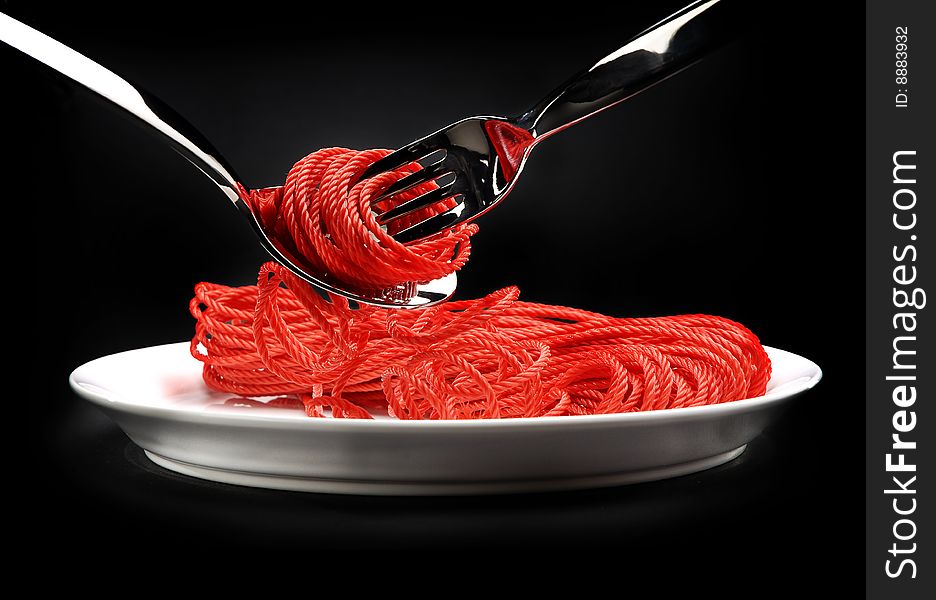 The red rope on a white plate, rolled up on a fork