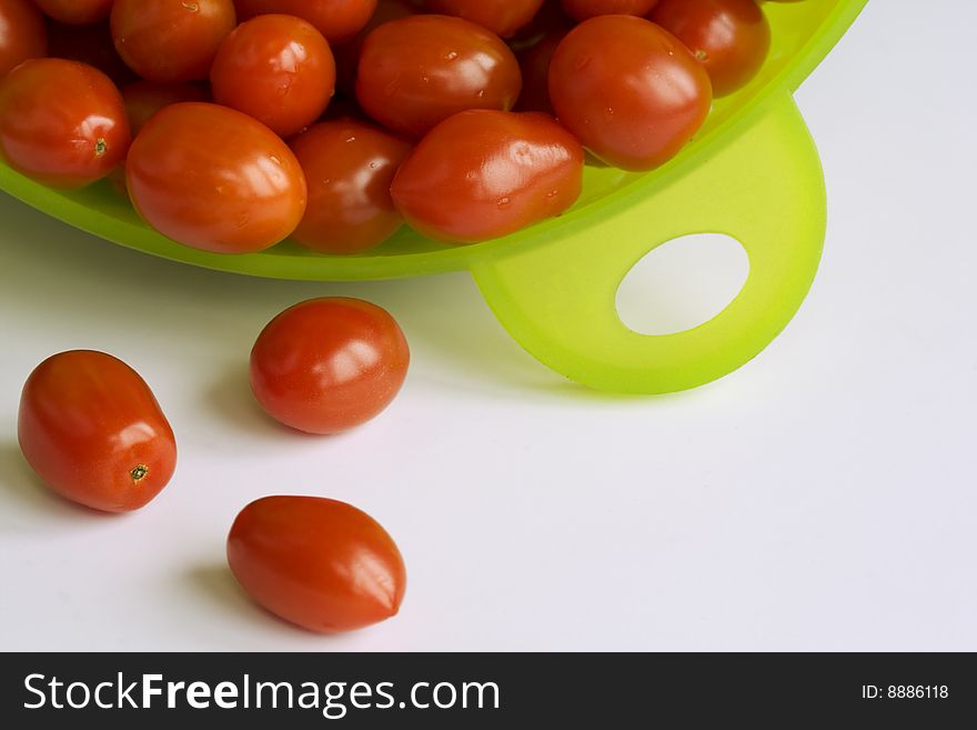 Many red tomatoes in the  green colander.