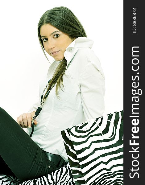 Half body view of young fashion model with white blouse and black blouse, sitting on the floor with zebra shopping bag and cushions. Isolated on white background.