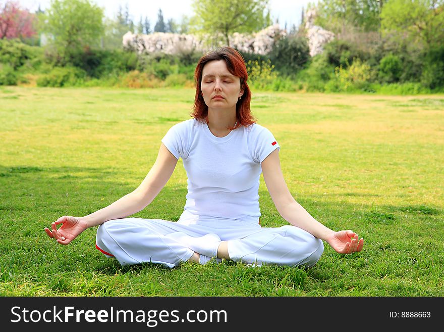 Women sit yoga style on the grass
