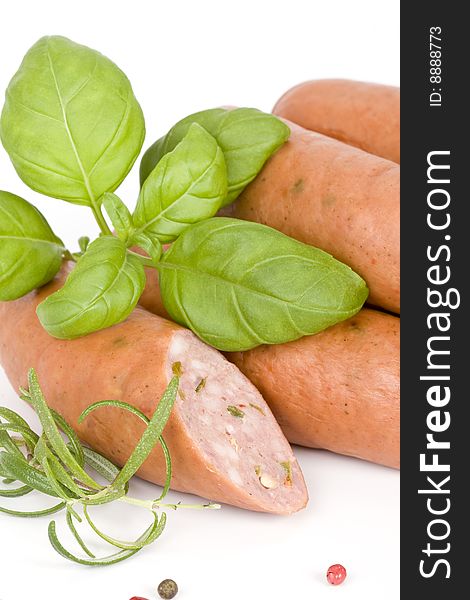 Detail of sausages with basil, rosemary and pepper on a white background