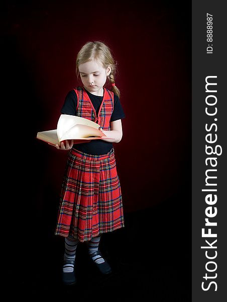 Serious schoolgirl with red book over dark. Serious schoolgirl with red book over dark