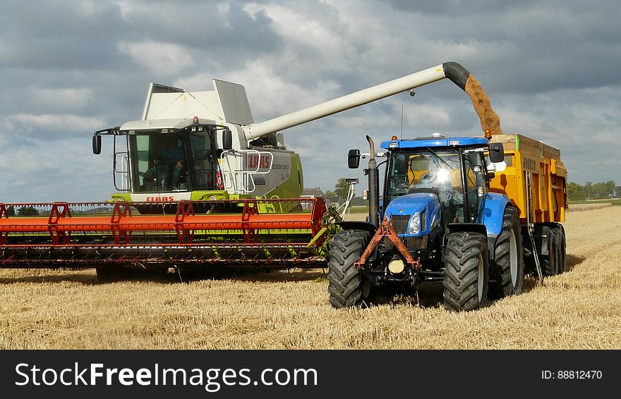 Blue Tractor Next To White Farm Vehicle At Daytime