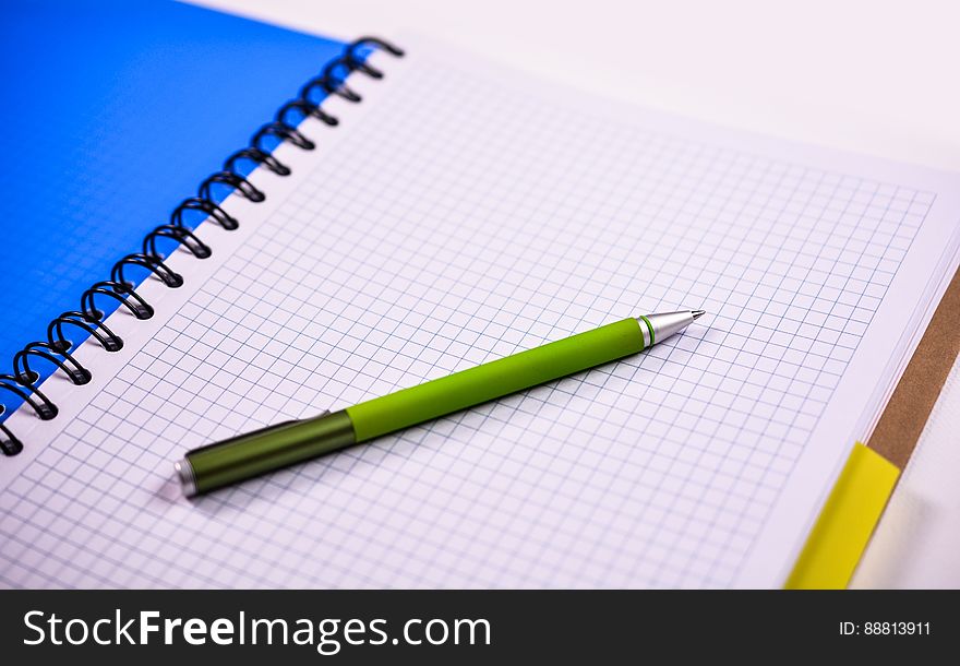 A close up of a pen on an open blank notebook. A close up of a pen on an open blank notebook.
