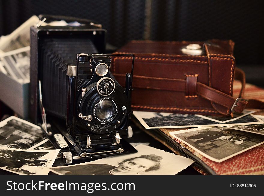 Vintage camera and case with photographs spread on table. Vintage camera and case with photographs spread on table.