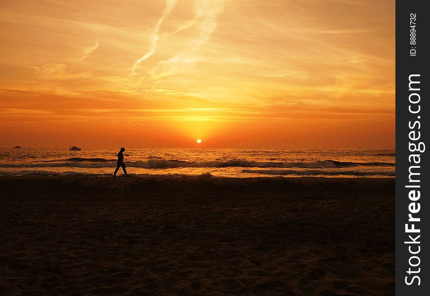 A person jogging on beach at sunset.