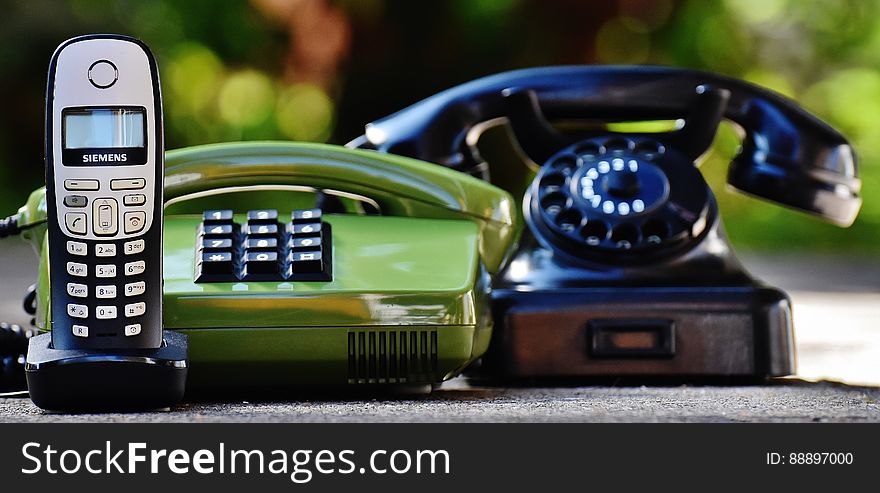 Black and Green Rotary Telephones Beside Cordless Home Telephone
