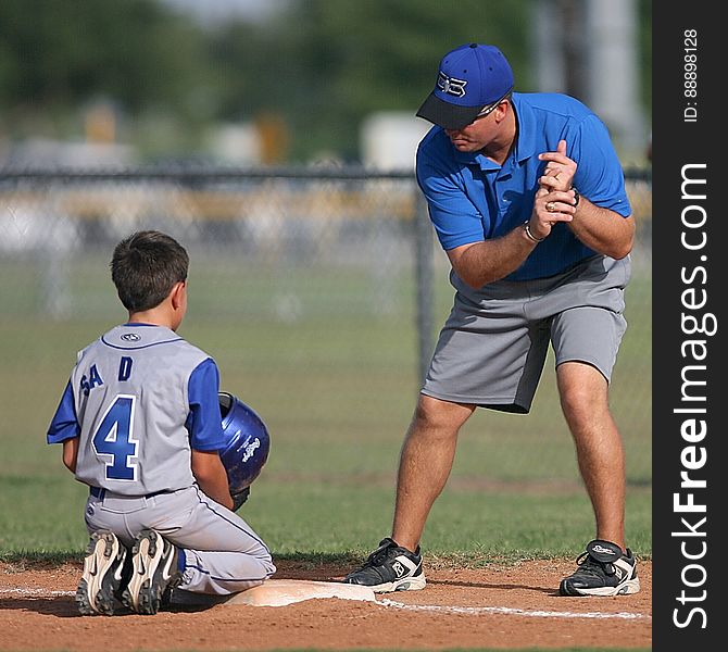 A baseball coach training a young player on the field.