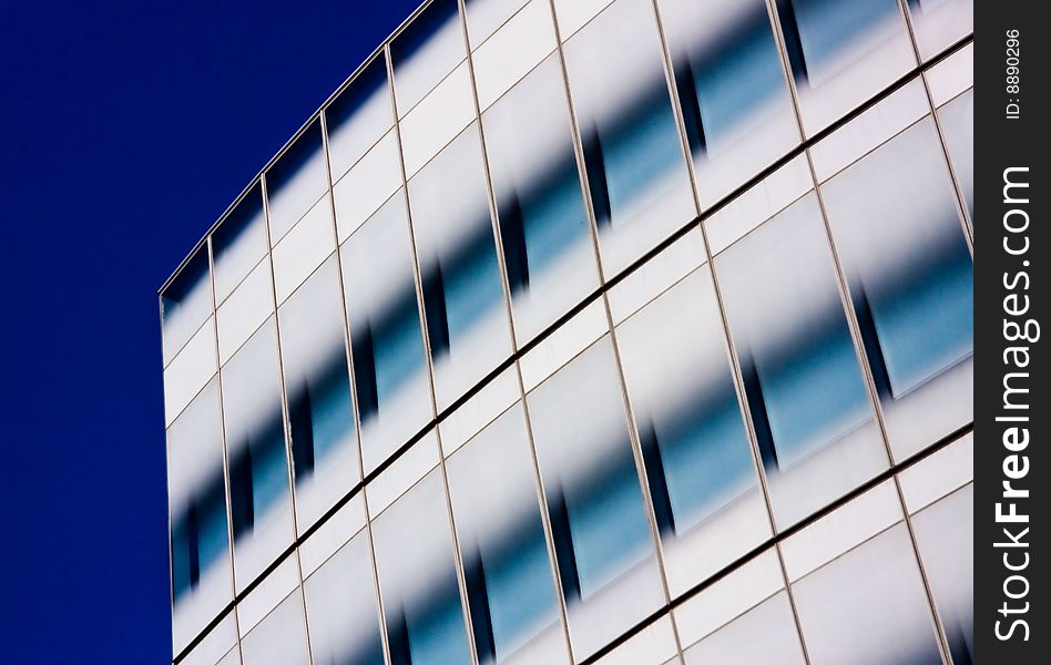 View of modern office building windows against a deep blue sky. View of modern office building windows against a deep blue sky.