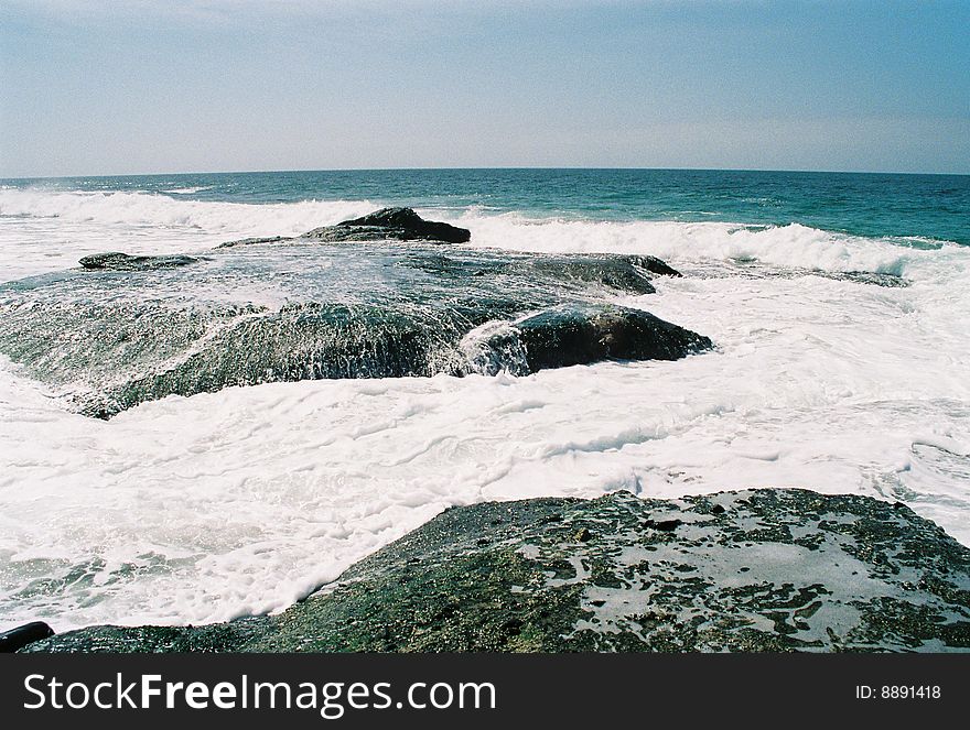 Ocean warer swallows rocks as waves roll in. Ocean warer swallows rocks as waves roll in.