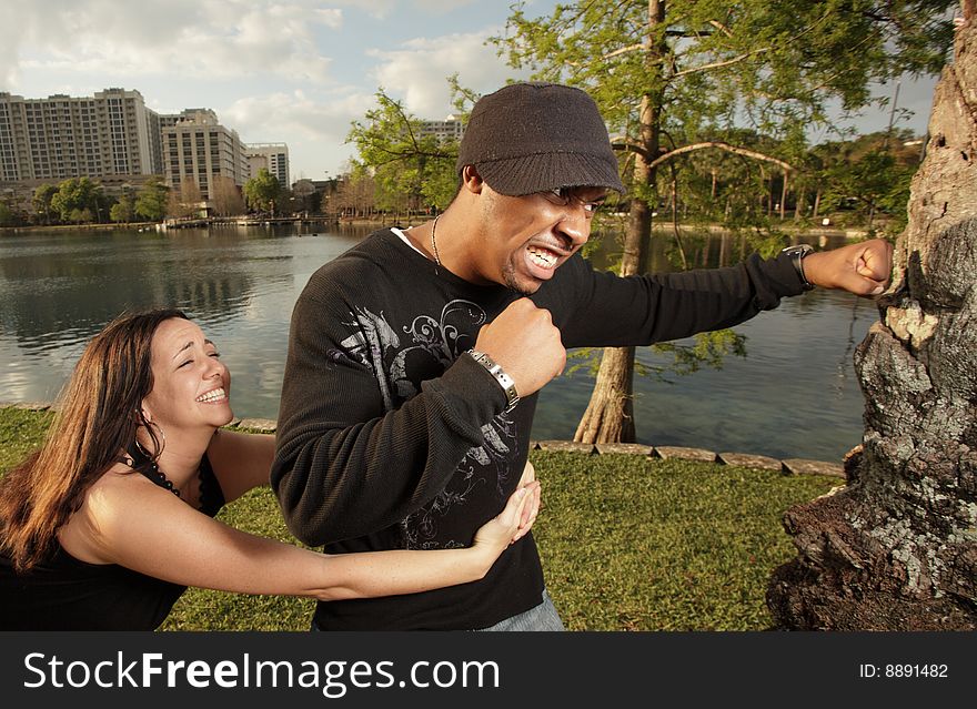 Man fighting a tree while his girlfriend is trying to hold him back