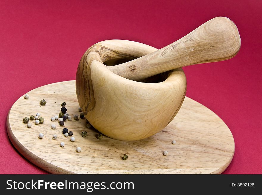 Mixed Pepper Grains on the cutting board with mortar.