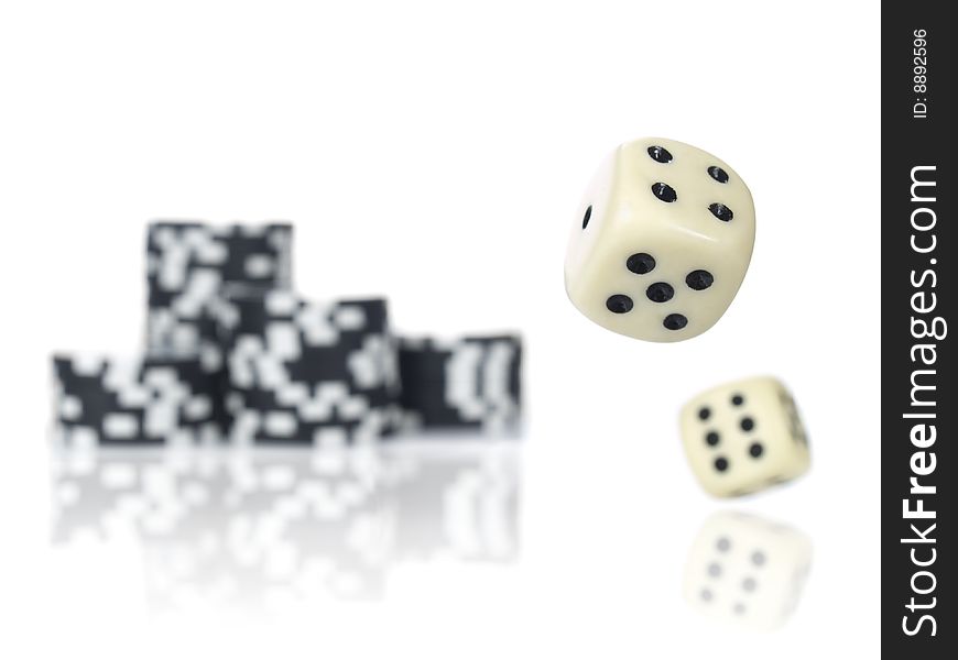 Pair of dice rolling in front of stacked black poker chips. Pair of dice rolling in front of stacked black poker chips.