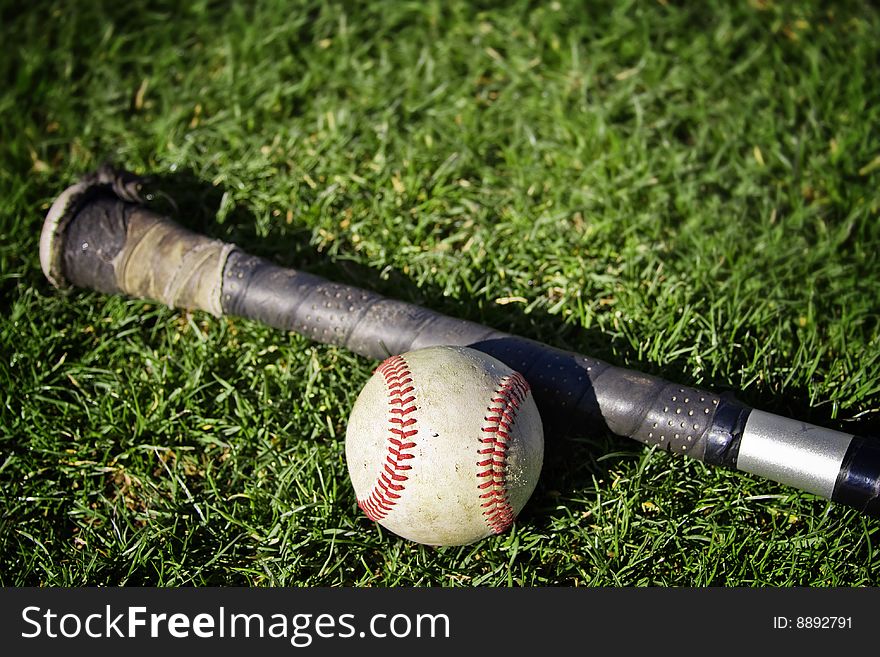 A baseball and a hat on a grassy baseball field. Shallow depth of field