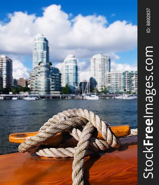 A rope is coiled around a cleat with Vancouver, B.C. cityscape in background. A rope is coiled around a cleat with Vancouver, B.C. cityscape in background.