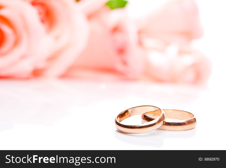 Wedding rings in front of roses, shallow focus on rings