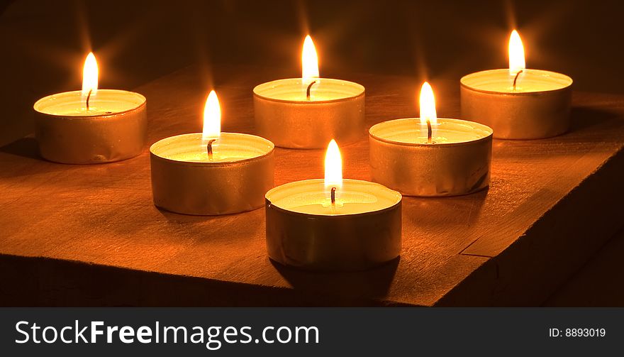 Many lighted candles on a dark background.