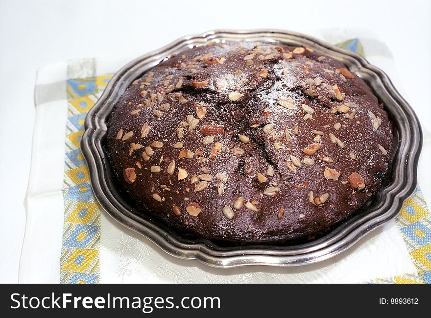 Chocolate cake with nuts and powdered sugar on table-napkin. Chocolate cake with nuts and powdered sugar on table-napkin