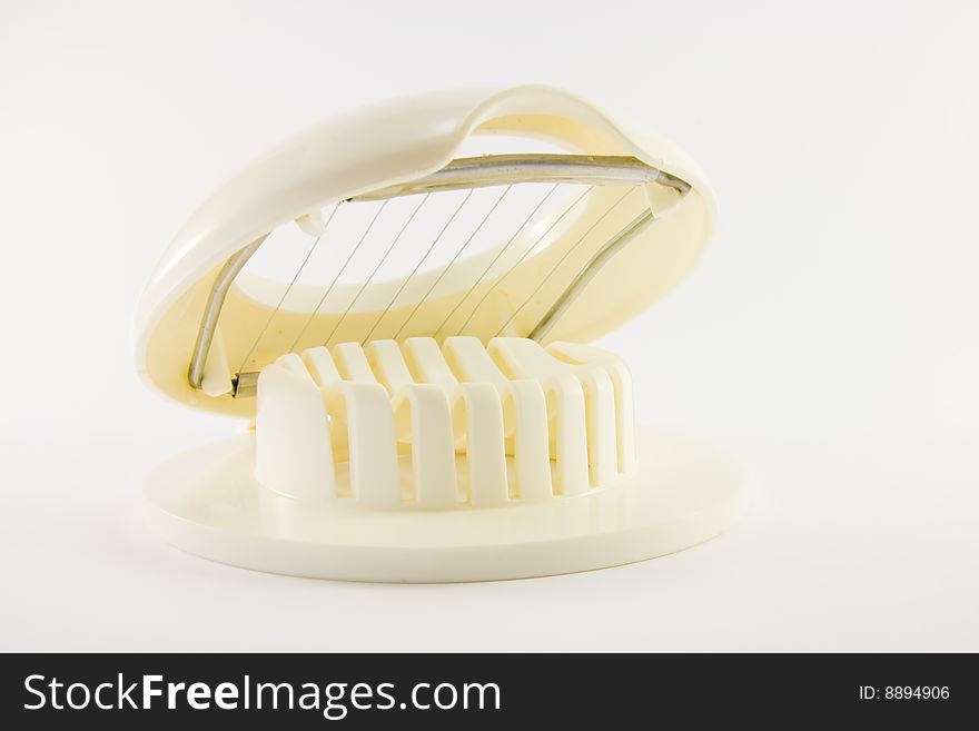 White plastic open egg slicer on a whit background