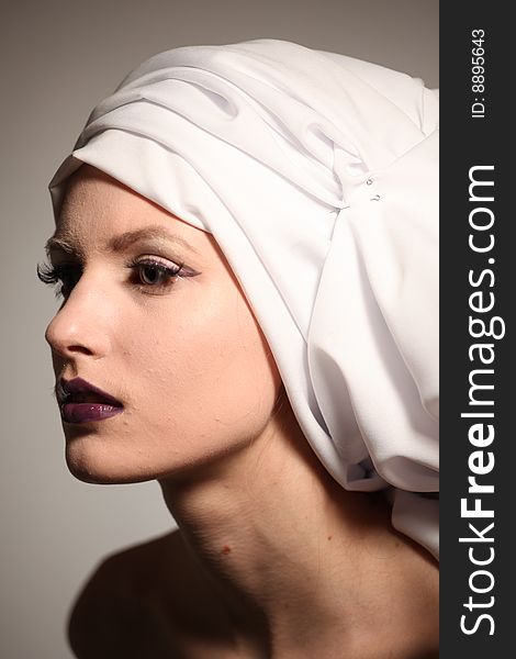 Portrait of the beautiful young woman with a bright make-up and a white fabric on a head