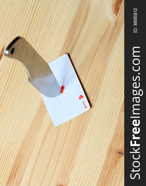 Direct hit to playing card with missile knife on wooden background