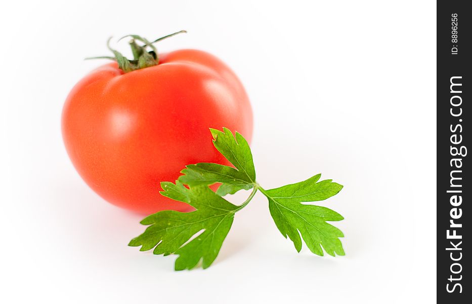A leaf of parsley in front of a tomato. A leaf of parsley in front of a tomato.