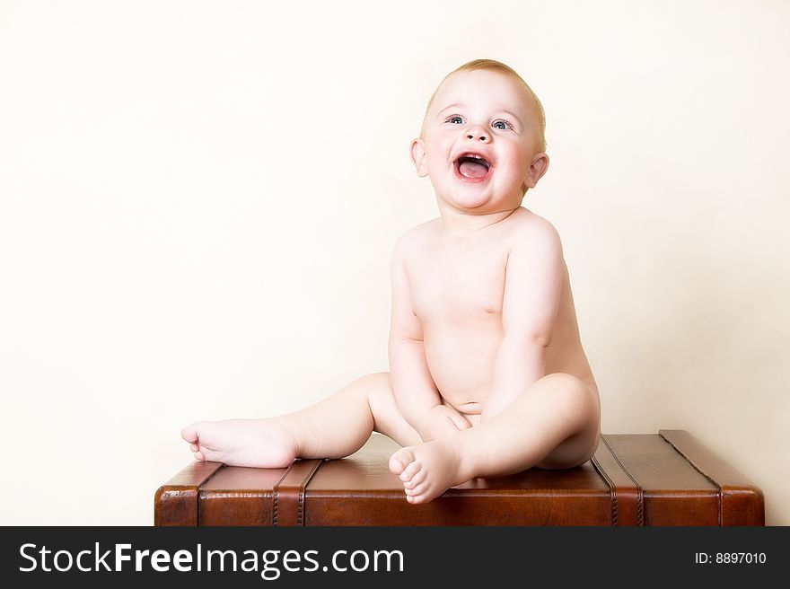 Young baby sitting on an old style suitcase